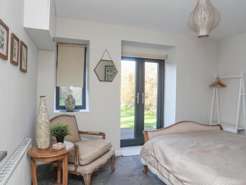 a bedroom with a bed and a chair and a window at Haulfryn in Moelfre
