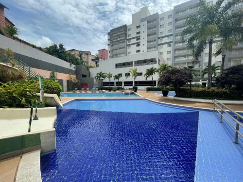 uma piscina com água azul em frente a um edifício em Flat 405 - Condomínio Veredas do Rio Quente - Diferenciado com ar na sala e no quarto em Rio Quente
