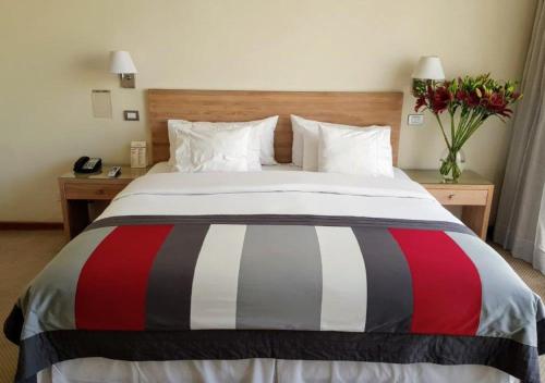 a bedroom with a bed with a red white and black striped blanket at Hotel Casino Talca in Talca