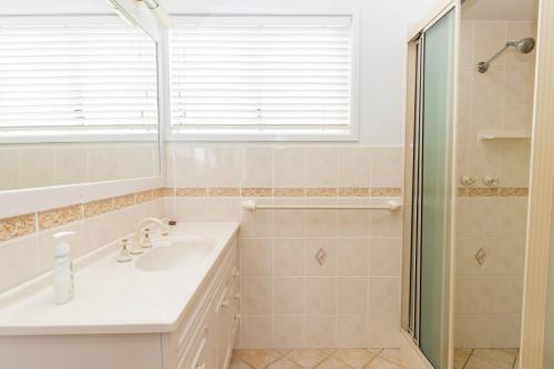 uma casa de banho branca com um lavatório e um chuveiro em Silversands Beach House em Berrara