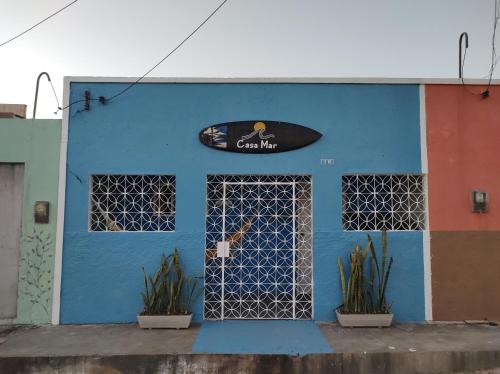 un edificio azul con una tabla de surf. en Casa Mar, en Baía Formosa