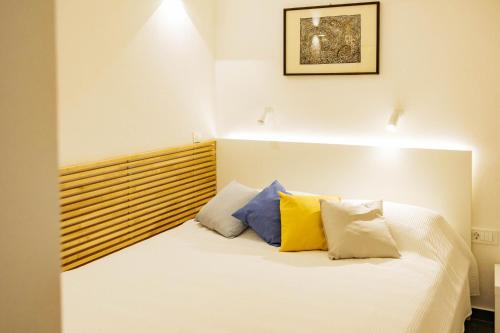 a bedroom with a white bed with yellow and blue pillows at Vila Jakopič apartments in Ljubljana