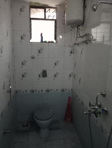 a bathroom with a toilet and a window at LUXURY 1 bedroom flat in Madgaon
