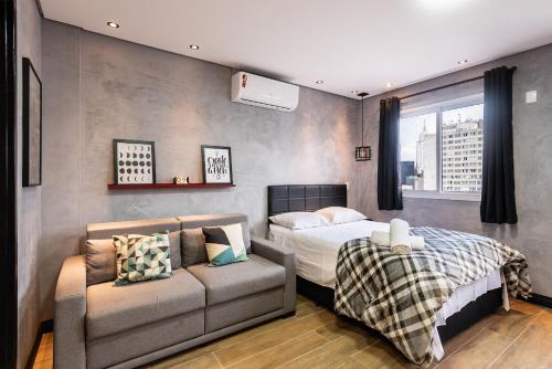 1 dormitorio con 1 cama y 1 sofá en Sky155 - Studio c/ Vaga Próx. à Estação da Luz: Seu Refúgio Urbano!, en São Paulo