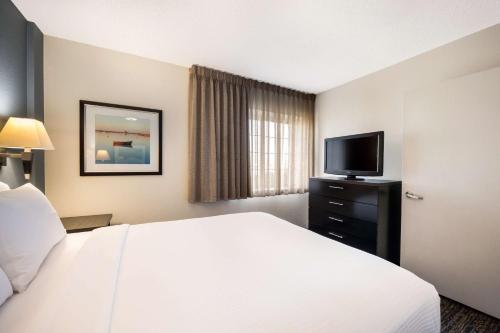 Sonesta Simply Suites Pittsburgh Airport في Imperial: غرفة فندقية بسرير وتلفزيون بشاشة مسطحة