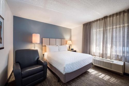 a hotel room with a bed and a chair at Sonesta Simply Suites Detroit Troy in Troy