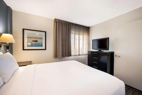 a hotel room with a bed and a flat screen tv at Sonesta Simply Suites Boston Braintree in Braintree