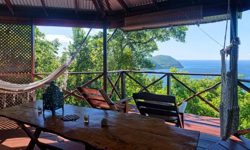 a wooden table and chairs on a porch with a hammock at Manicou River Resort in Portsmouth