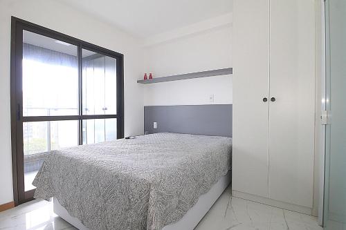 1 dormitorio con cama y ventana grande en Refúgio acolhedor com vista mar e piscina compartilhada, en Salvador