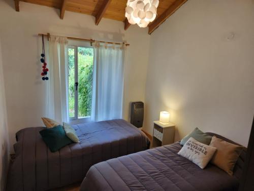 a bedroom with two beds and a window at La Serena casa in El Bolsón