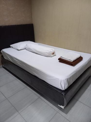 uma cama grande com lençóis brancos e almofadas em GRIYA BUNDA em Lumajang