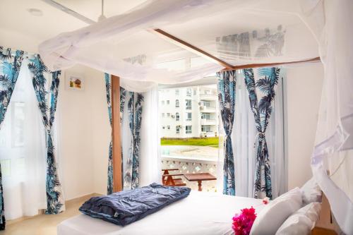um quarto com uma cama com cortinas azuis e brancas em Flamingo Naks Suite (Malindi's Hidden Gem) em Malindi