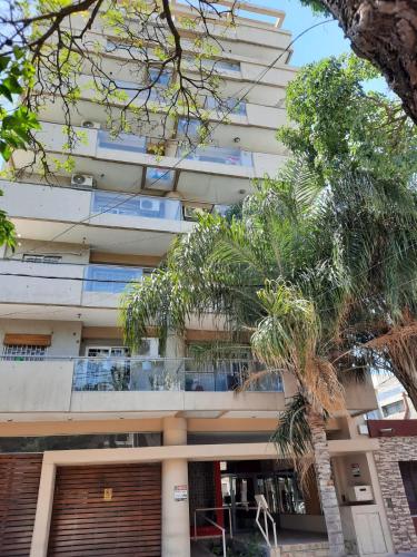 un edificio alto y blanco con palmeras delante en Departamento centro Santiago del Estero en Santiago del Estero