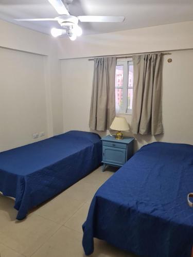 a bedroom with two blue beds and a window at Departamento centro Santiago del Estero in Santiago del Estero