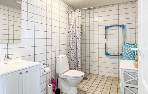 a white tiled bathroom with a toilet and a sink at Hus 74 in Allinge