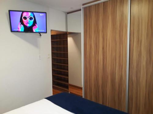 a room with a tv on the wall and a bed at Hospedagem Casa de Pedro in Santos