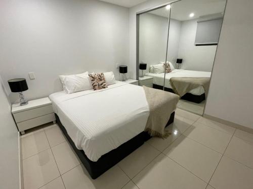 a bedroom with two beds and a mirror at Magnum Serviced Apartments in Darwin