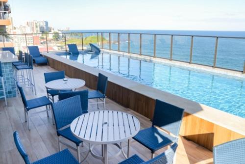 un balcón con mesas y sillas y una piscina en Refúgio acolhedor com vista mar e piscina compartilhada, en Salvador