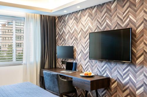 a hotel room with a desk and a flat screen tv at Almond Business Hotel in Nicosia