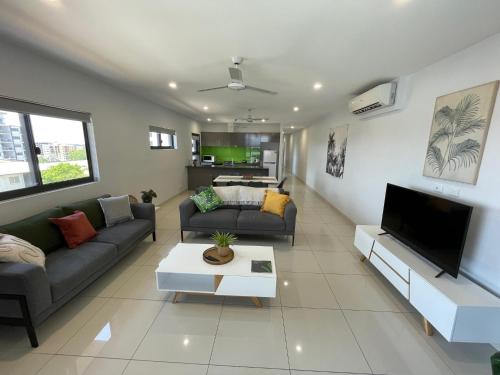 a living room with two couches and a tv at Magnum Serviced Apartments in Darwin