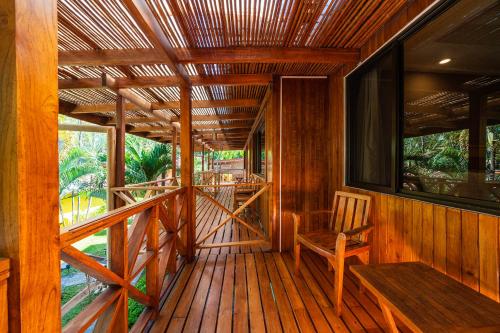 a wooden porch with a bench and a chair on it at Hotel Arco Iris in Tamarindo