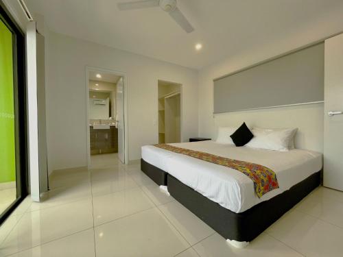 a bedroom with a large bed and a bathroom at Magnum Serviced Apartments in Darwin