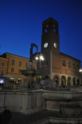 a fountain in front of a building with a clock tower at Hotel Amelia in Fano