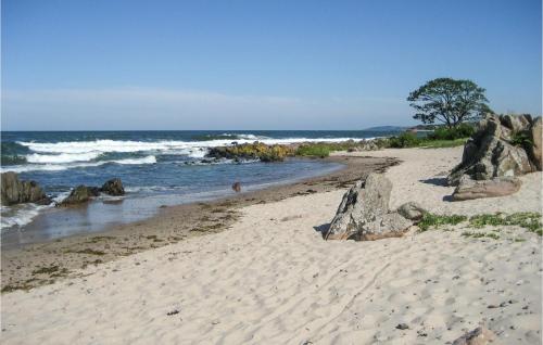 a sandy beach with rocks and the ocean at Amazing Apartment In Allinge With Wifi in Allinge
