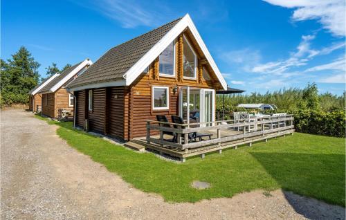 a log cabin with a large porch and a yard at Cozy Home In Tranekær With Kitchen in Tranekær