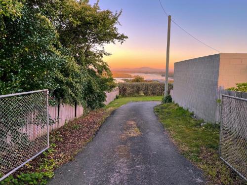 an empty road next to a fence with the sunset in the background at Quaint and intimate 1-bed seaside cottage in Bridport