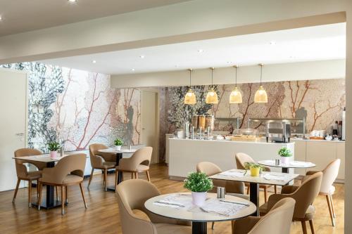 a restaurant with tables and chairs and a kitchen at Almond Business Hotel in Nicosia