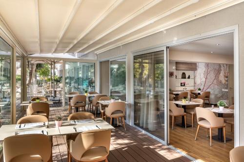 a restaurant with tables and chairs and windows at Almond Business Hotel in Nicosia