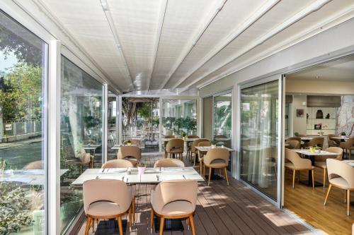 a restaurant with glass walls and tables and chairs at Almond Business Hotel in Nicosia