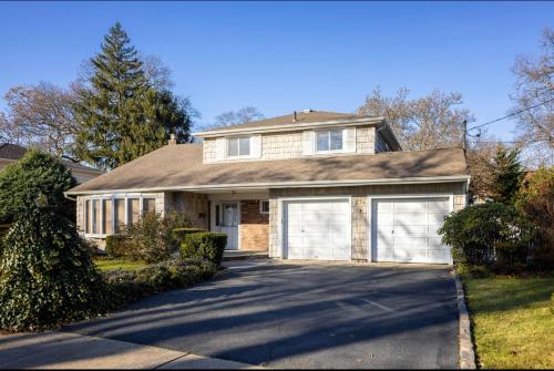 a house with two garage doors on a driveway at Cheerful Studio Getaway/Garden/By Lake State Park. in West Hempstead
