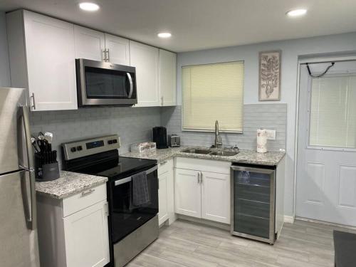 a kitchen with white cabinets and black appliances at Modern 2/1 in Parrish FL Sleeps 6 Quiet Dead End St 1/2 Acre Wow in Parrish