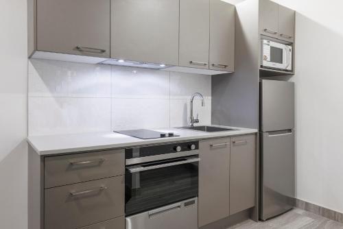 a kitchen with white cabinets and a sink and a refrigerator at Adina Citylife Wellington in Wellington
