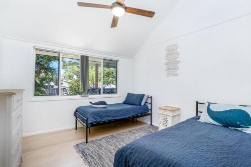 a bedroom with a bed and a chair and windows at Castaway Cottage - Rainbow Beach in Rainbow Beach