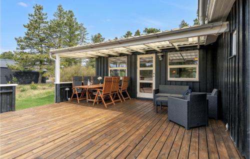 una terrazza in legno con tavolo e sedie. di Cozy Home In Blåvand With Wifi a Blåvand