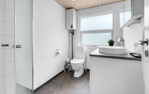La salle de bains est pourvue de toilettes, d'un lavabo et d'une fenêtre. dans l'établissement Cozy Home In Blvand With Wifi, à Blåvand