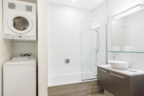 a white bathroom with a sink and a washing machine at CityLife Wellington in Wellington