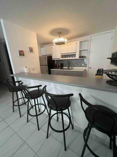 a kitchen with chairs and a bar with a counter top at Casa Rosado Villa Marina Fajardo Yunque Seven Seas in Fajardo