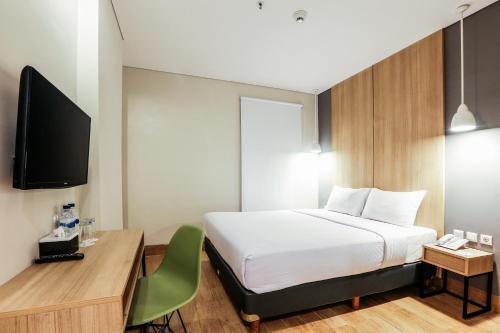een slaapkamer met een bed, een bureau en een televisie bij Hotel Citradream Semarang in Semarang