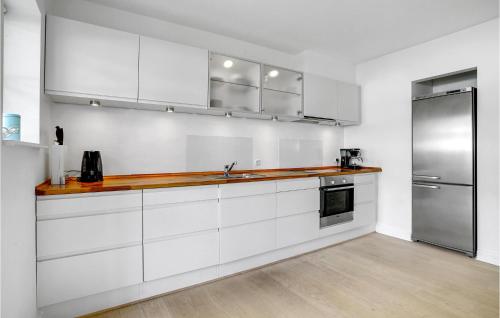 a kitchen with white cabinets and a stainless steel refrigerator at Lake Front Apartment In Nykøbing Sj in Rørvig