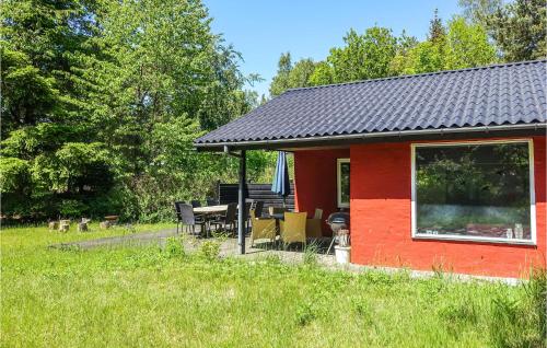 a red cabin with a table and chairs in a field at 3 Bedroom Lovely Home In Rønne in Rønne