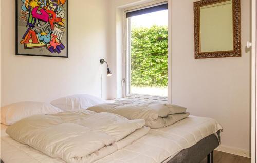 Bett in einem Zimmer mit Fenster in der Unterkunft 3 Bedroom Lovely Home In Rnne in Rønne