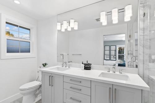 a white bathroom with a sink and a toilet at @ Marbella Lane - 3BR w/sweeping views of Bay Area in San Mateo
