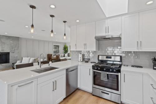 a white kitchen with a sink and a stove at @ Marbella Lane - 3BR w/sweeping views of Bay Area in San Mateo