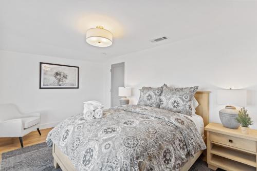 a white bedroom with a bed and a chair at @ Marbella Lane - 3BR w/sweeping views of Bay Area in San Mateo