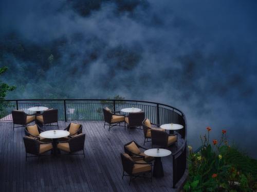 una terraza con mesas, sillas y nubes en el cielo en Elevate Bali, en Munduk