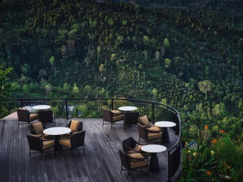 a deck with tables and chairs and a view of a mountain at Elevate Bali in Munduk